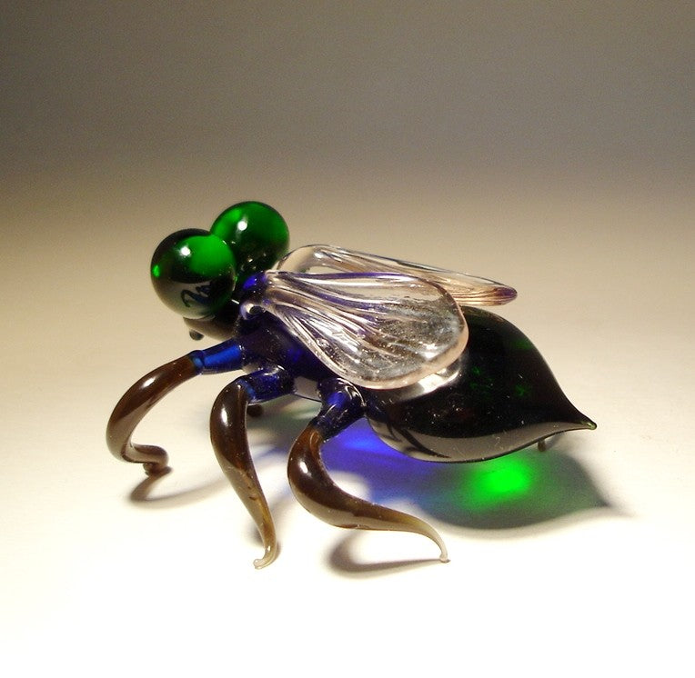 A detailed glass Green-Eyed Fly figurine, showcasing its vibrant green eyes and delicately crafted wings, positioned in a natural resting pose.