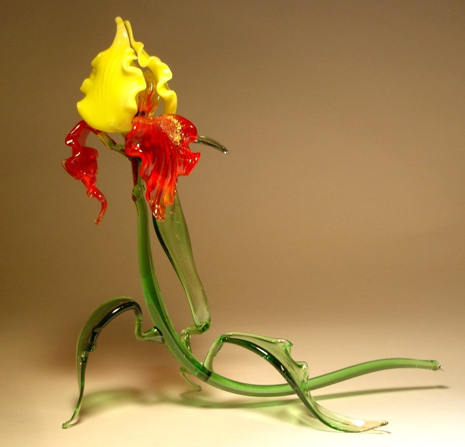 Side view of the glass iris figurine, highlighting the striking red and yellow colors in the petals and the detailed leaf structure.