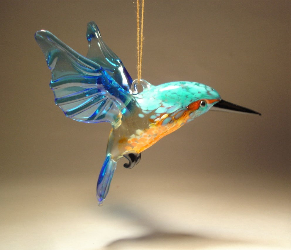 A side view of a glass kingfisher ornament, highlighting the intricate details of its blue wings.