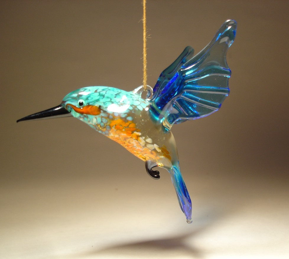 A vibrant glass kingfisher ornament figurine, showcasing its brilliant blue and orange plumage while being  suspended from a thread.