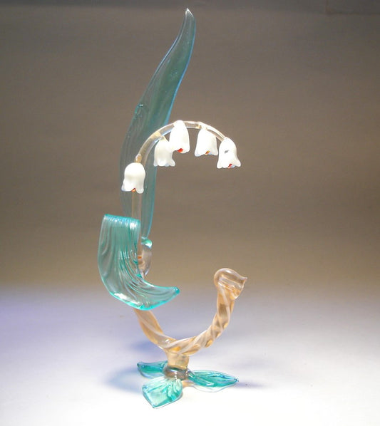 A delicate glass Lily of the Valley flower figurine, showcasing its slender stem, green leaves  and white bell-shaped flowers.