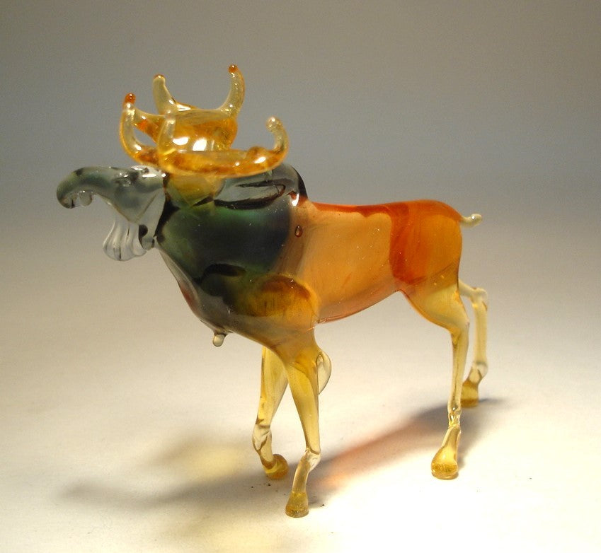 Close-up of a glass moose figurine, highlighting its impressive antlers and intricately detailed body in brown and grey.