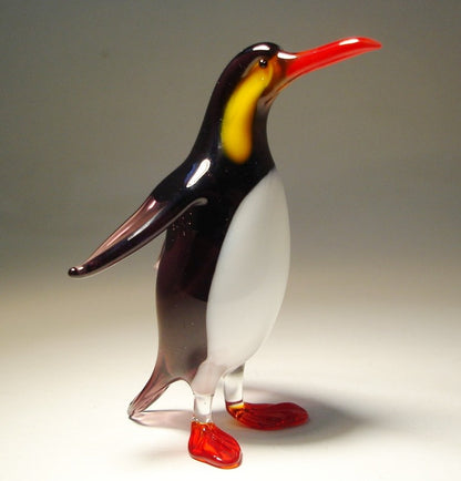 Side view of the glass penguin, highlighting its sleek black and white colors and red feet and beak.