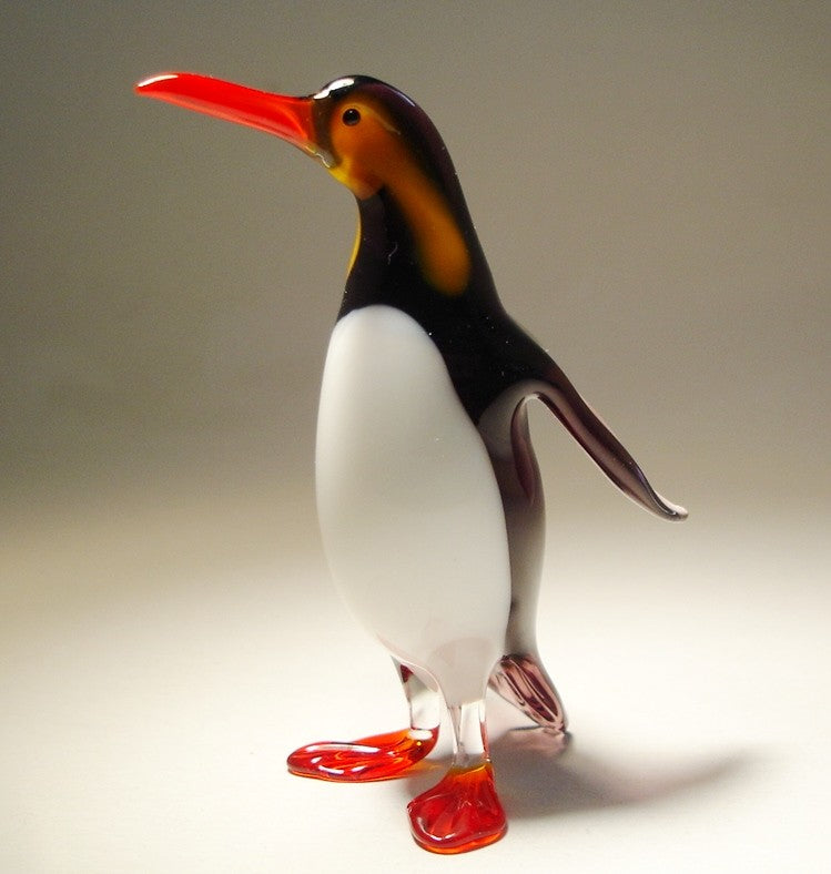 a Close-up view of a black and white glass penguin figurine with extended wings.