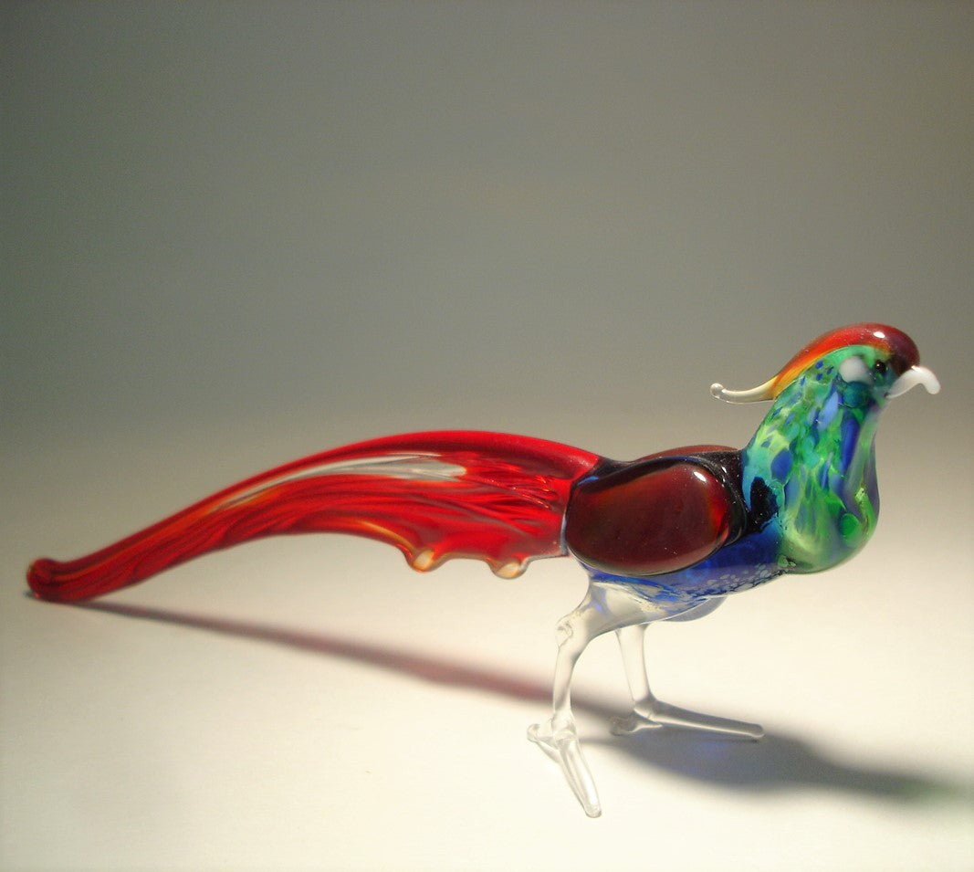 Side angle of the glass pheasant figurine, capturing the elegant curve of its long red tail feathers.