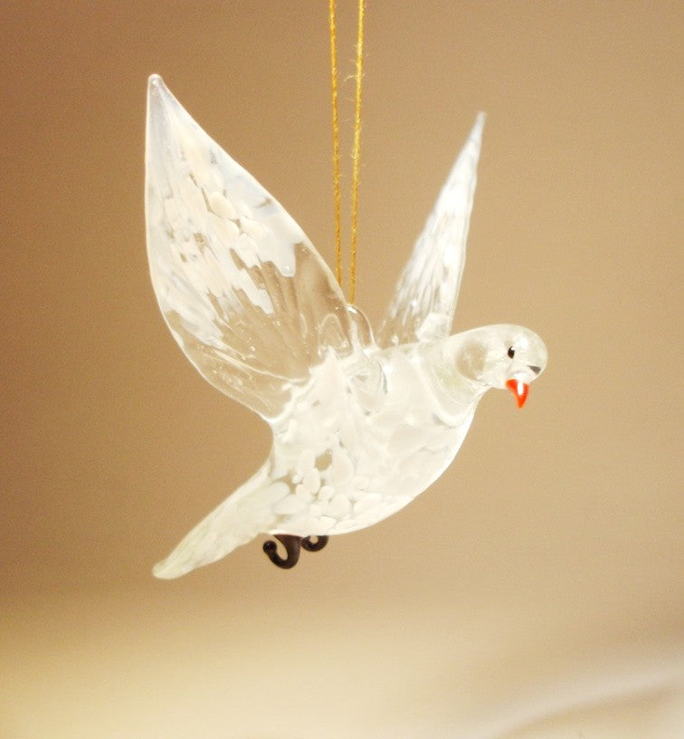 A delicate glass dove ornament gracefully suspended in mid-flight, showcasing its  intricate feather details in white and clear glass.