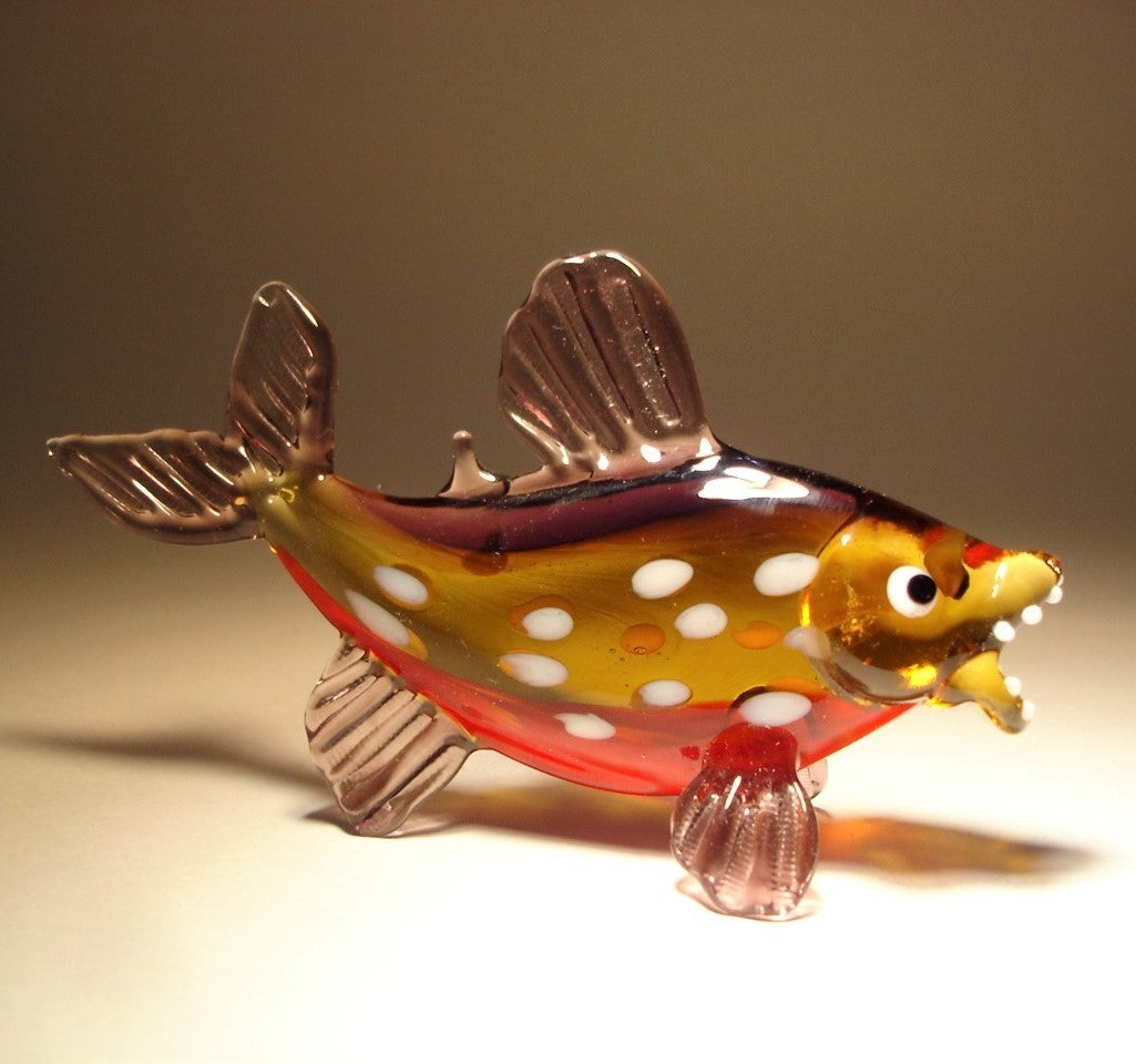 A striking glass piranha figurine with sharp white teeth, showcasing its fierce appearance.