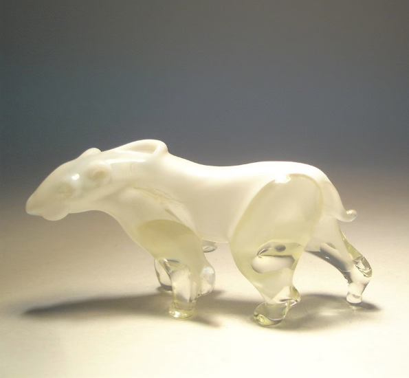 The glass white and clear figurine showcasing the intricate detailing of its paws and fur .