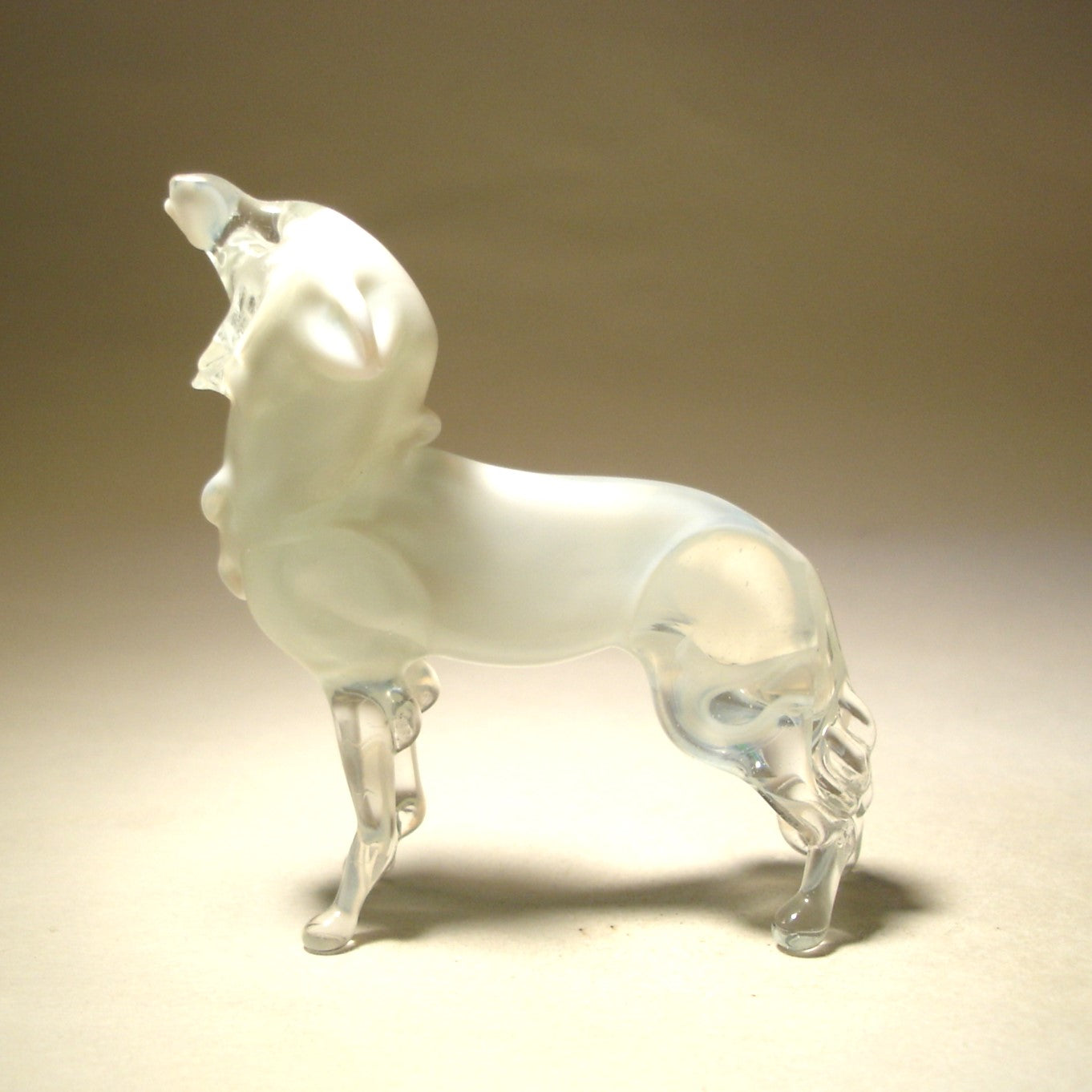 Side view of a stunning glass polar wolf figurine in a howling pose. 