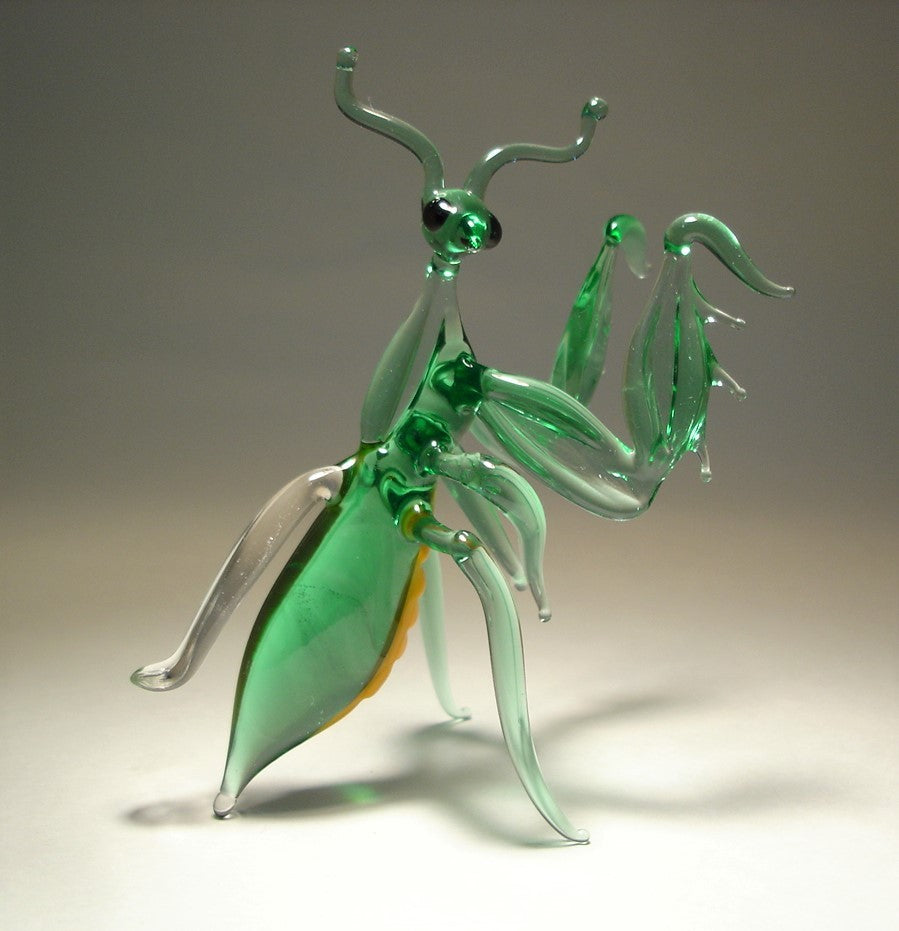 Side view of the glass praying mantis figurine, showcasing its long, slender body, delicate legs, and a clear glass wing.