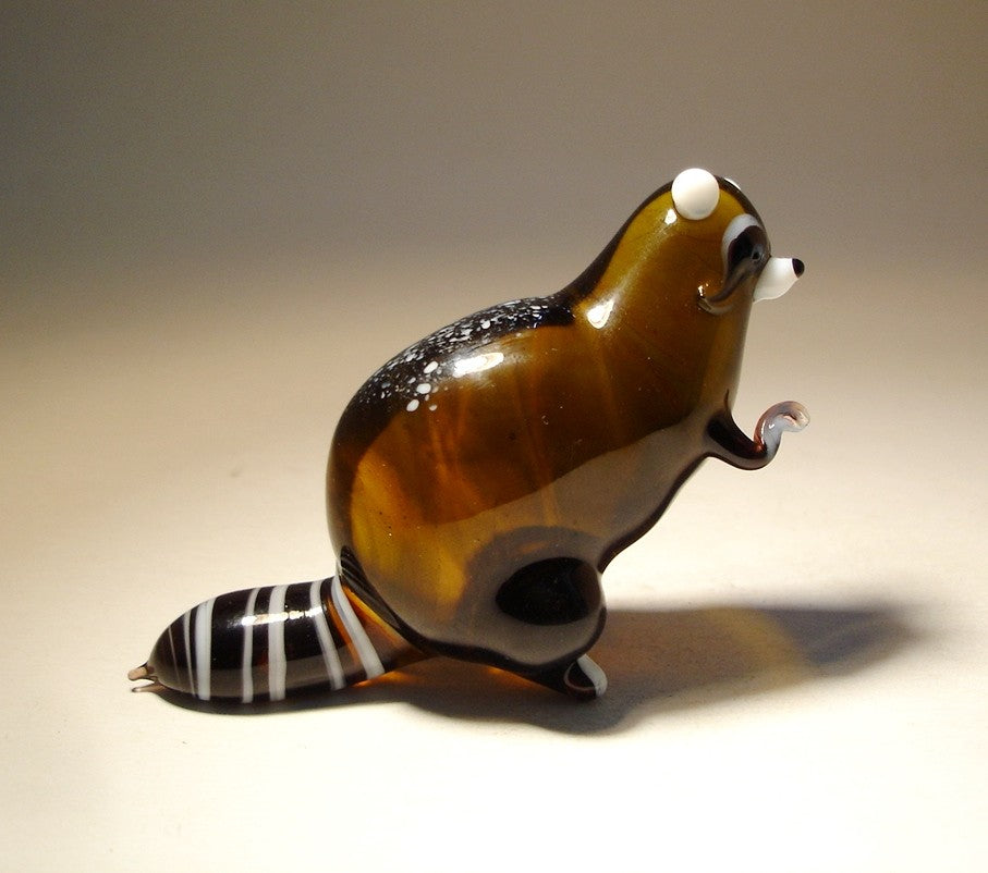 A handcrafted glass raccoon figurine standing upright.