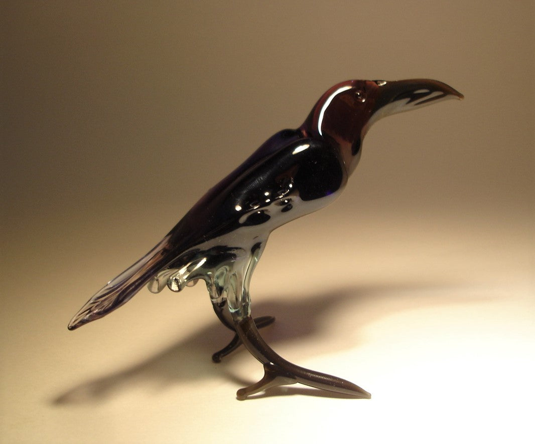 Front view of a glass black raven crow figurine, showcasing its dark purple head, glossy body and detailed underbelly.