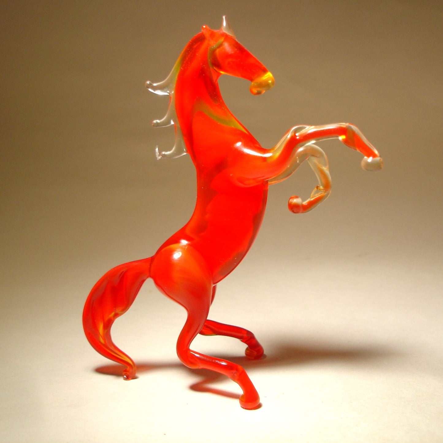 A front view of a red glass horse figurine rearing on its hind legs, showcasing its raised front legs and arched neck.