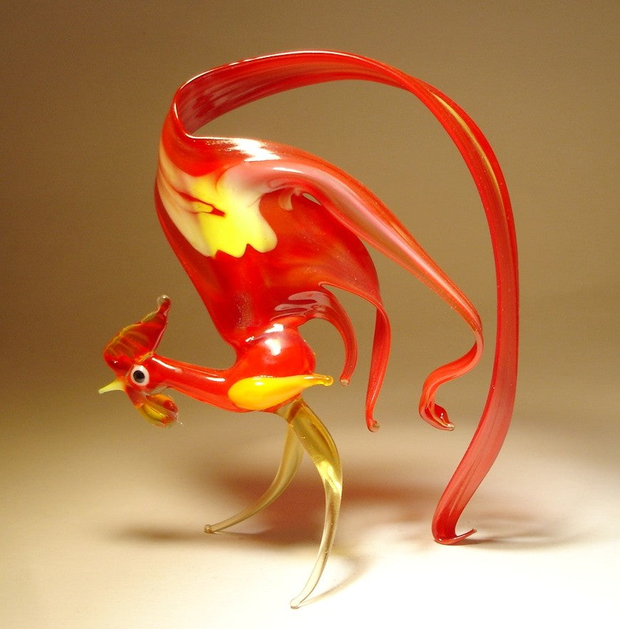 Another side view of the glass rooster figurine, highlighting the striking red tail and the intricate design of it's tail feathers