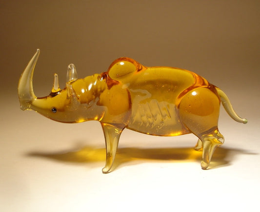 A front view of a glass rhinoceros figurine, showcasing its prominent horn, strong body, and detailed facial features.