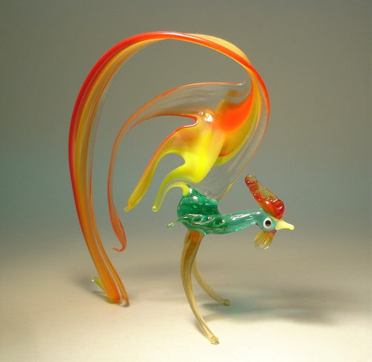 A glass figurine of a rooster with a vibrant red, and yellow arched tail that curves elegantly behind it.