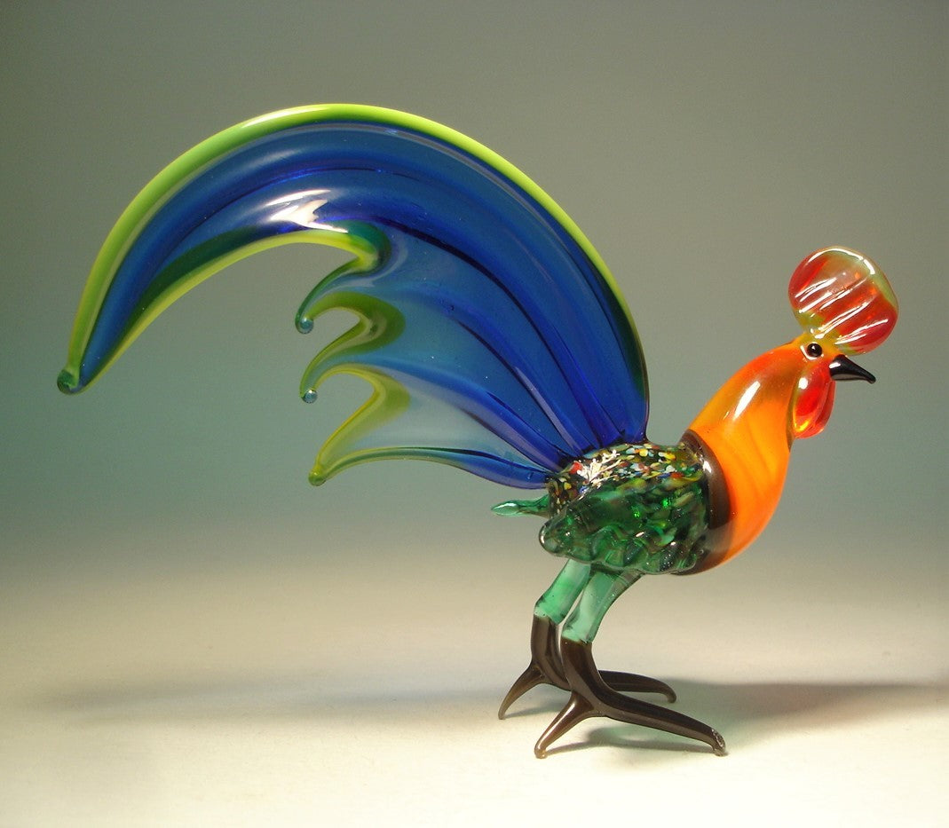 Right side view of the blue glass rooster figurine, highlighting the elegant curvature of its fan-shaped tail and orange neck