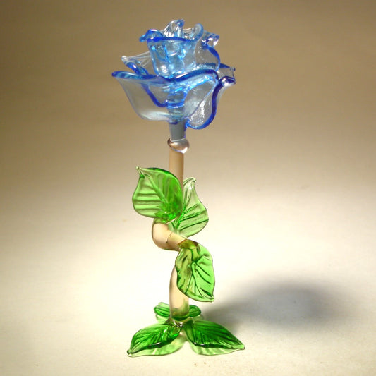 glass blue rose figurine standing on it's stem and three green leaves