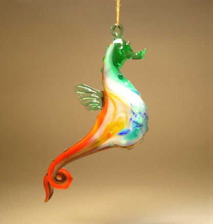 A vibrant glass seahorse ornament in hues of green, white, and red, gracefully suspended from a thread.