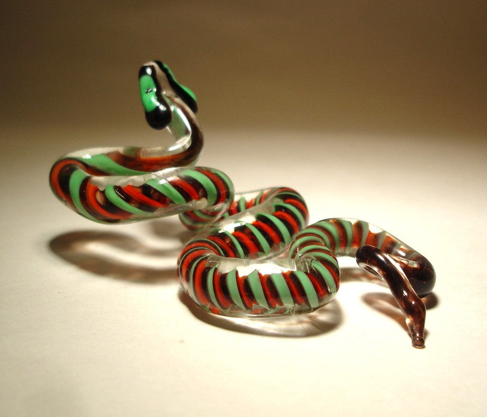 A front view of a glass snake figurine, showcasing its vibrant red and green body, in a winding, slithering posture that captures the movement of the snake.