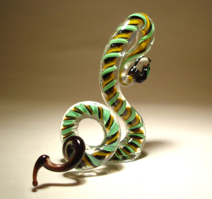 A side view of a glass snake figurine displaying vibrant green, black, and yellow colors, coiled in an agitated pose.