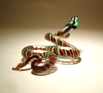 A top view of a red and green glass snake figurine with its head slightly raised as if in motion.