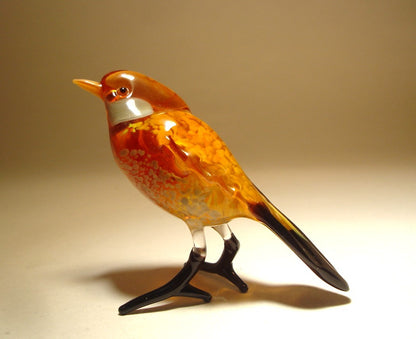 Side view of a glass sparrow figurine, showcasing its smooth brown and white feathers and a black tail