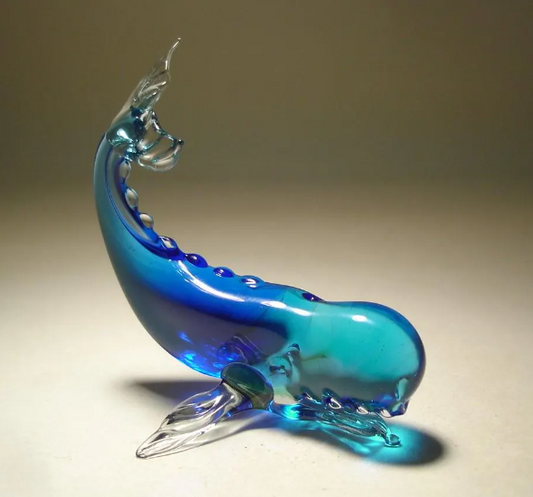 A side view of a blue glass sperm whale figurine, emphasizing its distinctive head and tail fluke.