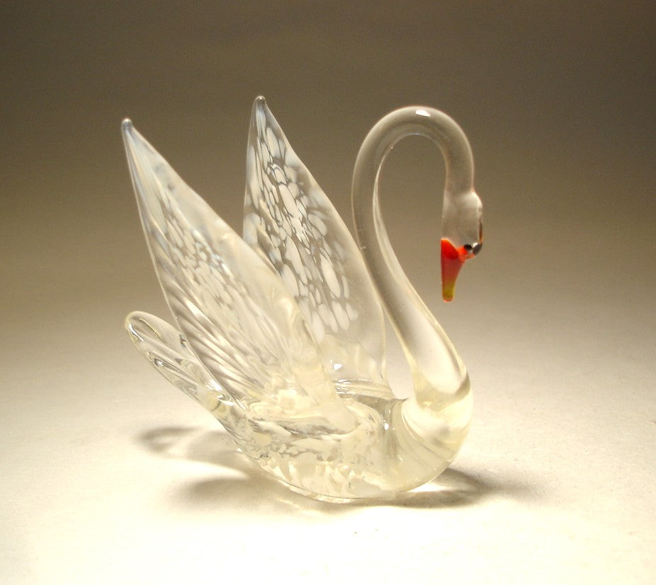 Close-up of a white and clear glass swan figurine with a red beak.