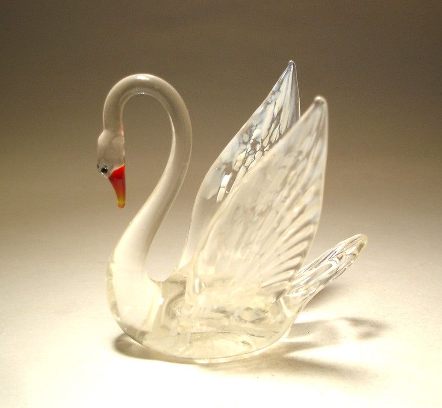 Anther side view of a graceful glass swan figurine, mostly clear with multiple white specs on its wings and tail.