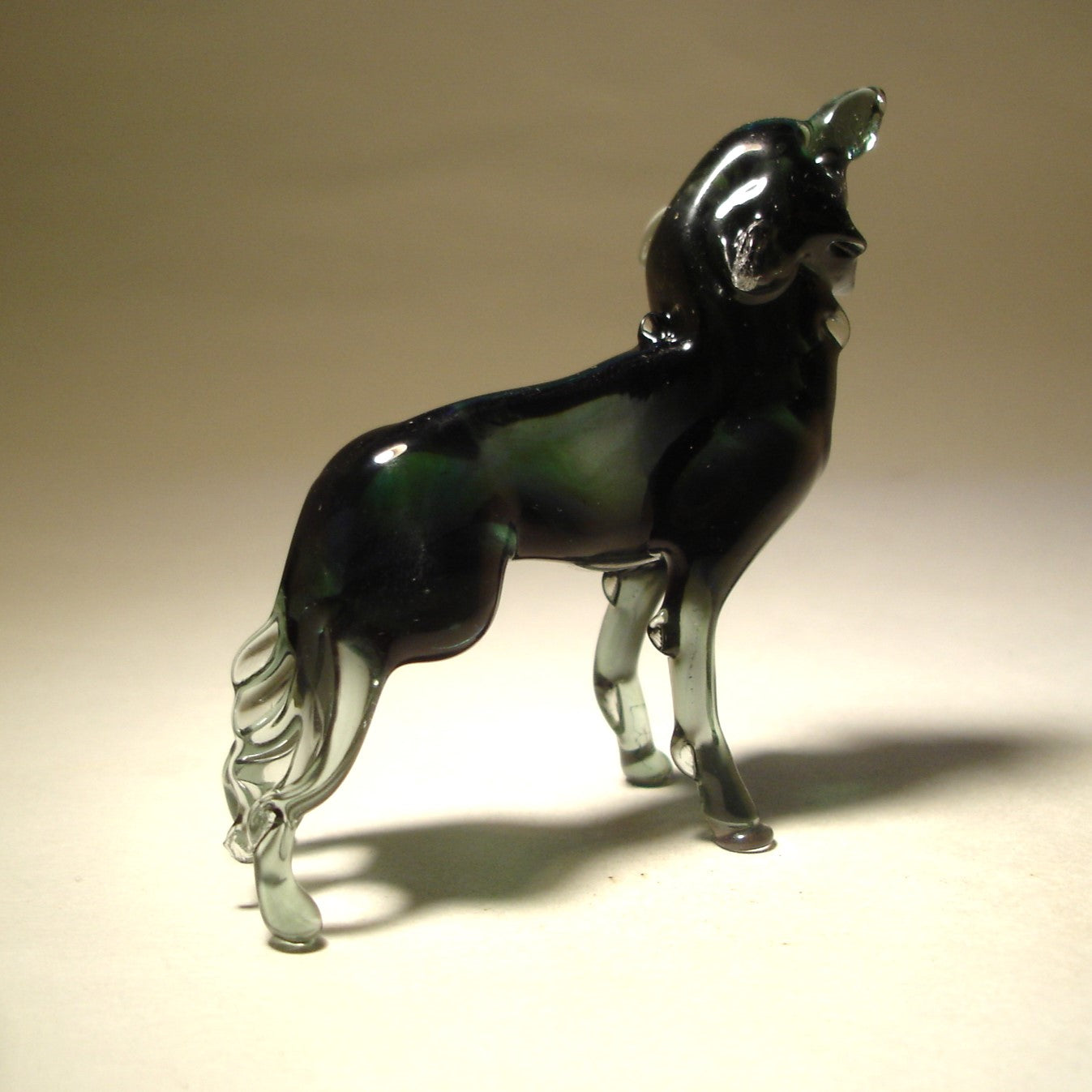 A back view of the glass wolf figurine, focusing on the curve of its body and the positioning of its tail, as it stands tall in a striking howling position.