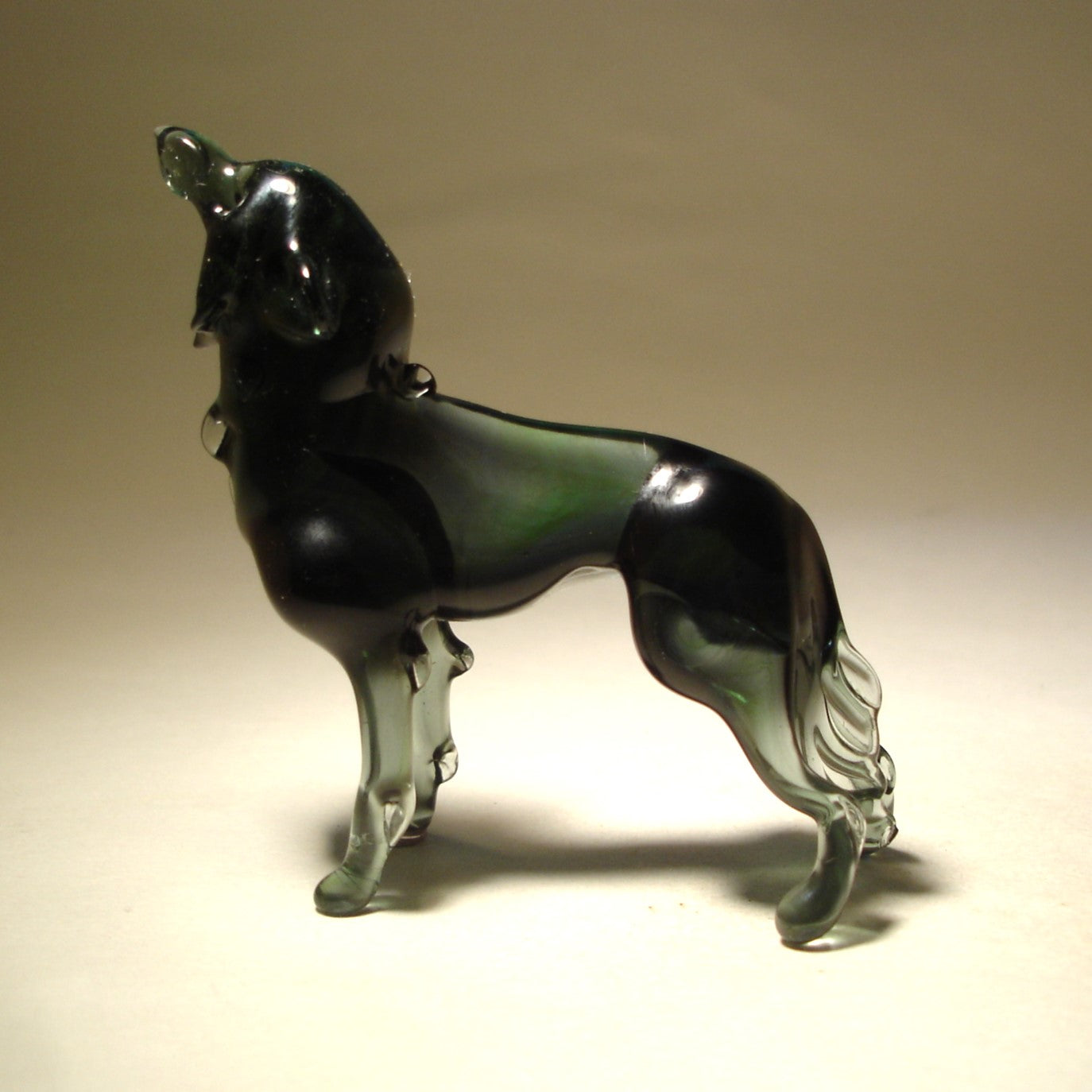 A side view of the glass wolf figurine, highlighting its arched back, raised snout, and extended legs.