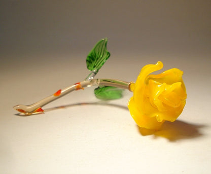 Glass yellow rose figurine in laying position to better discern the petals and a close-up of the red thorns.