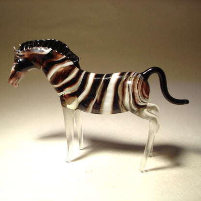 A glass zebra figurine with a sleek, glossy surface, showcasing the zebra’s iconic black and white stripes. 