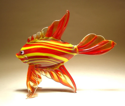 A side view of a red glass tropical fish figurine, highlighting its striped yellow pattern and detailed fins.