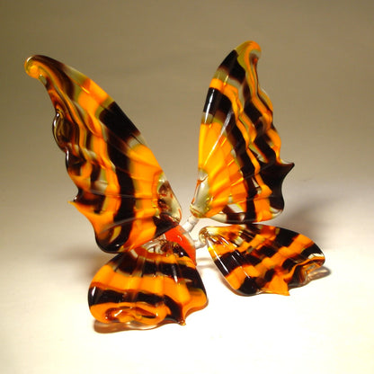 A close-up shot of the orange and black glass butterfly figurine, focusing on the striped wing patterns.