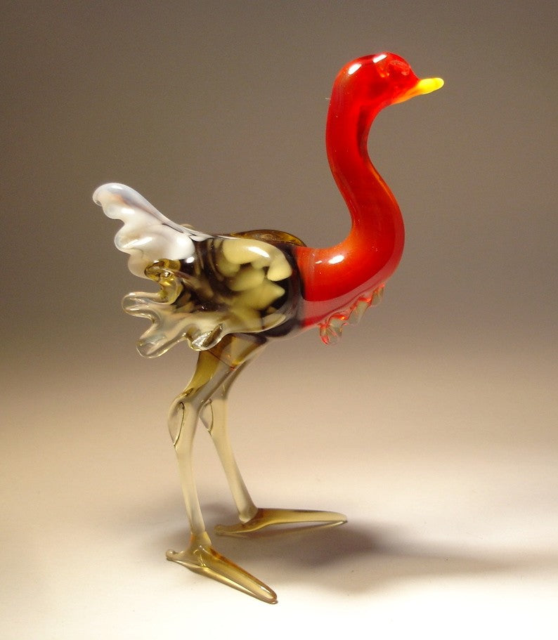 Close-up of a glass ostrich figurine featuring a sleek body and a striking red neck.